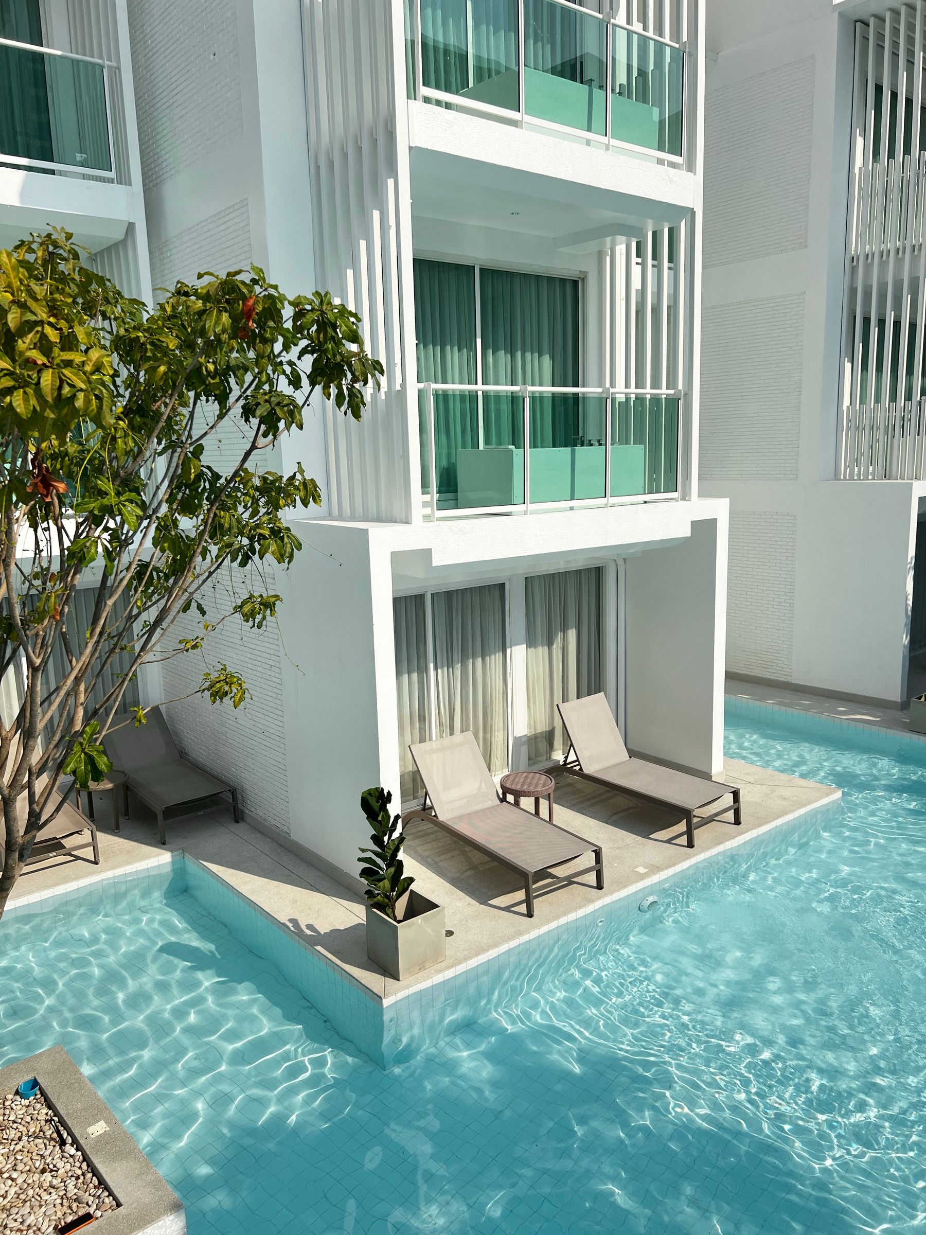 Poolside apartment terraces with balconies among tropical planting — illustrative photography
